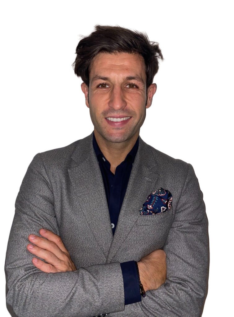 Hombre sonriente con traje y brazos cruzados.