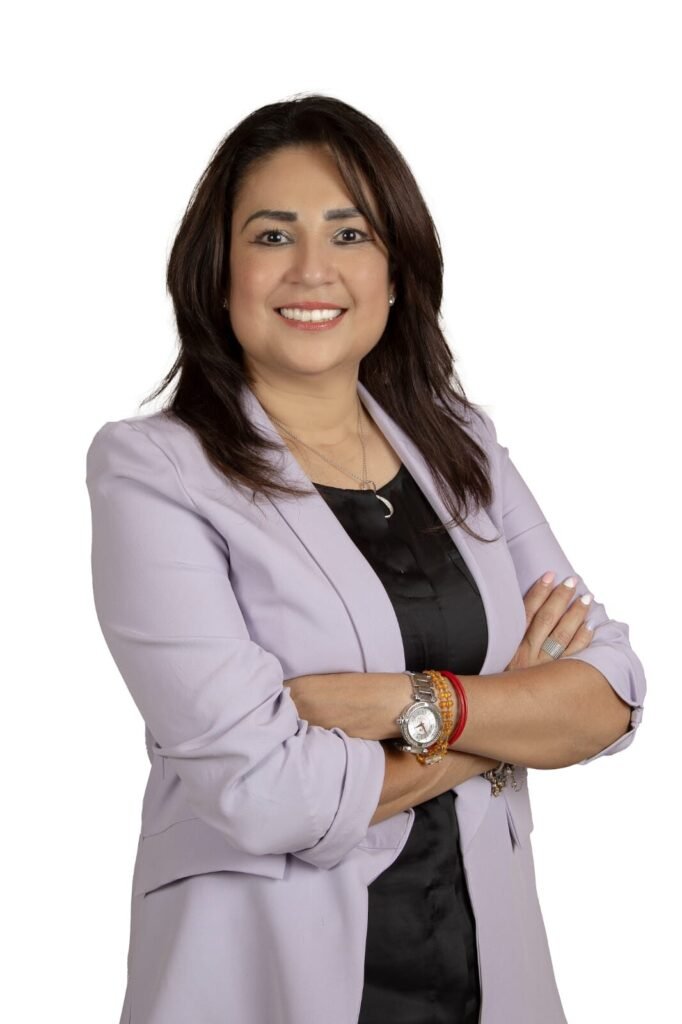 Mujer sonriente con brazos cruzados, fondo blanco.