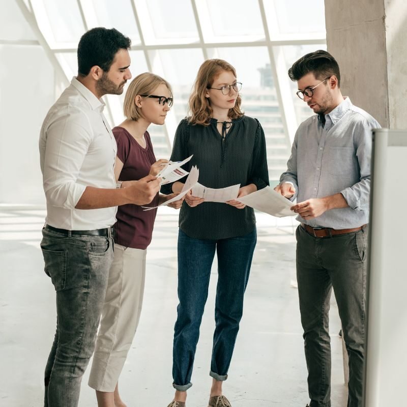 Cuatro personas revisan documentos en grupo.