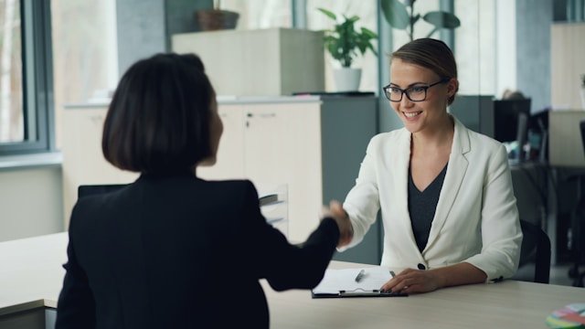 Dos mujeres estrechando manos en una reunión.
